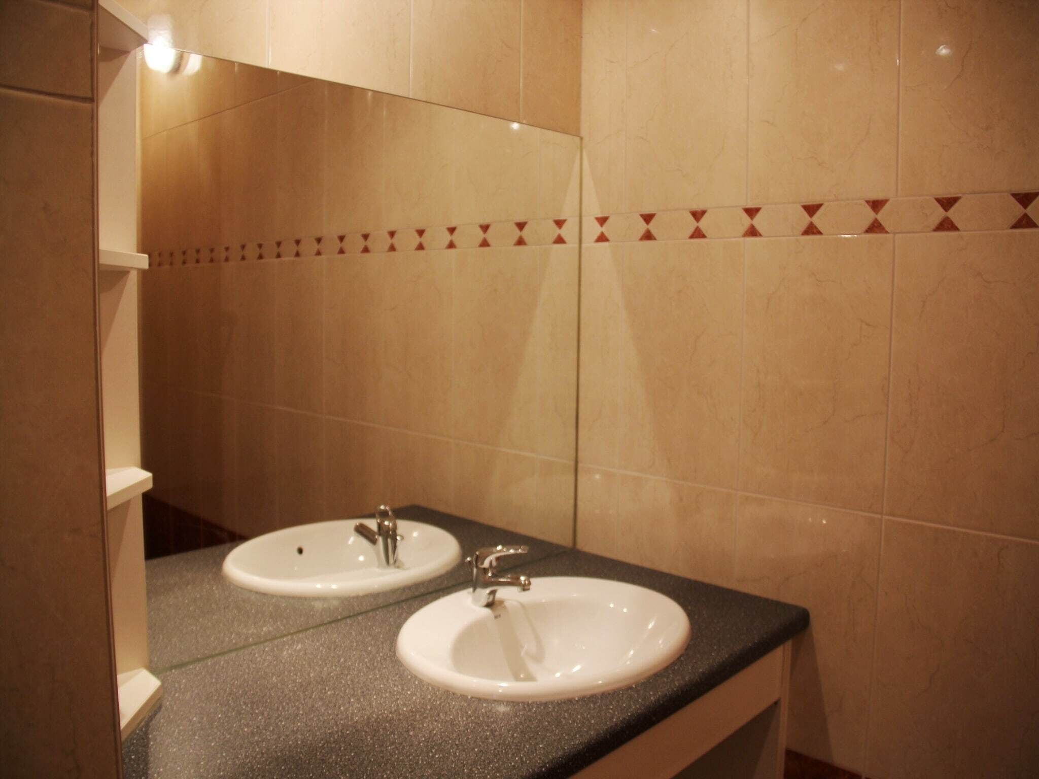 A bathroom with two sinks, a mirror, and a decorative tile border.