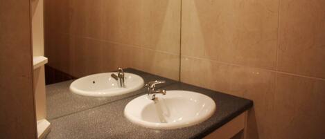A bathroom with two sinks, a mirror, and a decorative tile border.