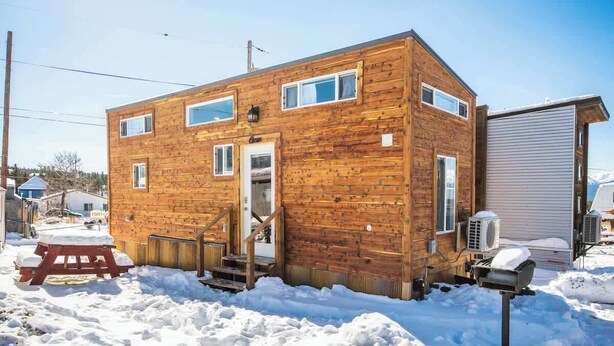 Een houten chalet met een voordeur, ramen en een overdekt terras.