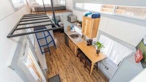 Een compacte keuken met een houten tafel, een ingebouwde magnetron en een klein spoelbakje.