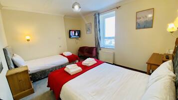 A hotel room with two single beds, a television, a window with a view, and a wooden nightstand.
