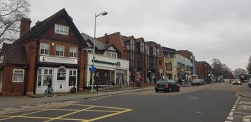 Una calle con edificios, incluyendo una tienda con un letrero que dice "The Tuck Shop".