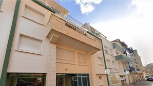 A multi-story residential building with a ground-level entrance, a balcony, and a visible window with a reflection. - Central Arcachon: 400m from Beach, T2 with Balcony, Parking, and Pet-Friendly (Arcachon)