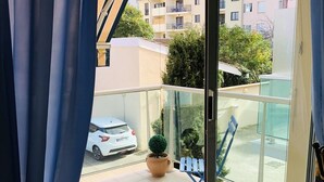 A balcony with a potted plant, a folding chair, and a white car parked outside. - Central Arcachon: 400m from Beach, T2 with Balcony, Parking, and Pet-Friendly (Arcachon)