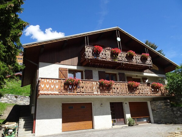 Un bâtiment à deux étages doté d’un balcon, de volets en bois et de jardinières.