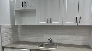Una cocina con armarios blancos, una encimera y un fregadero.