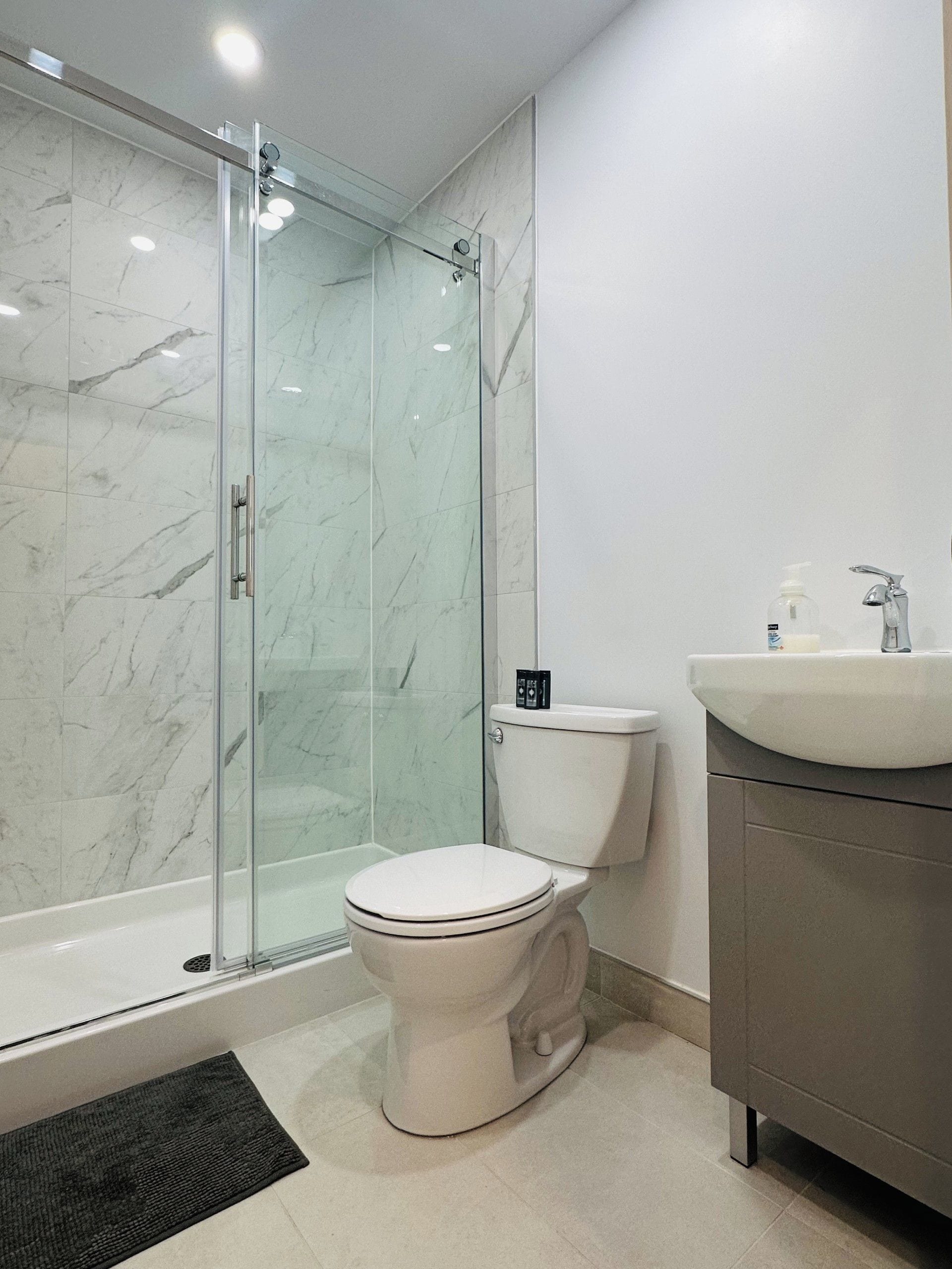Un baño con ducha de vidrio, inodoro y lavabo.