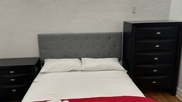 A bedroom with a bed, two bedside tables, a dresser, and two wall-mounted lights.