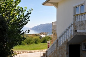 A coastal property with a stone staircase, a view of the sea, and a grassy area.