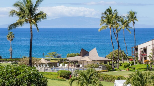 A resort with a pool, palm trees, and a view of the ocean. - Hale Kamaole 127 Ground floor condo, easy access to best beach on Maui! (Kihei)