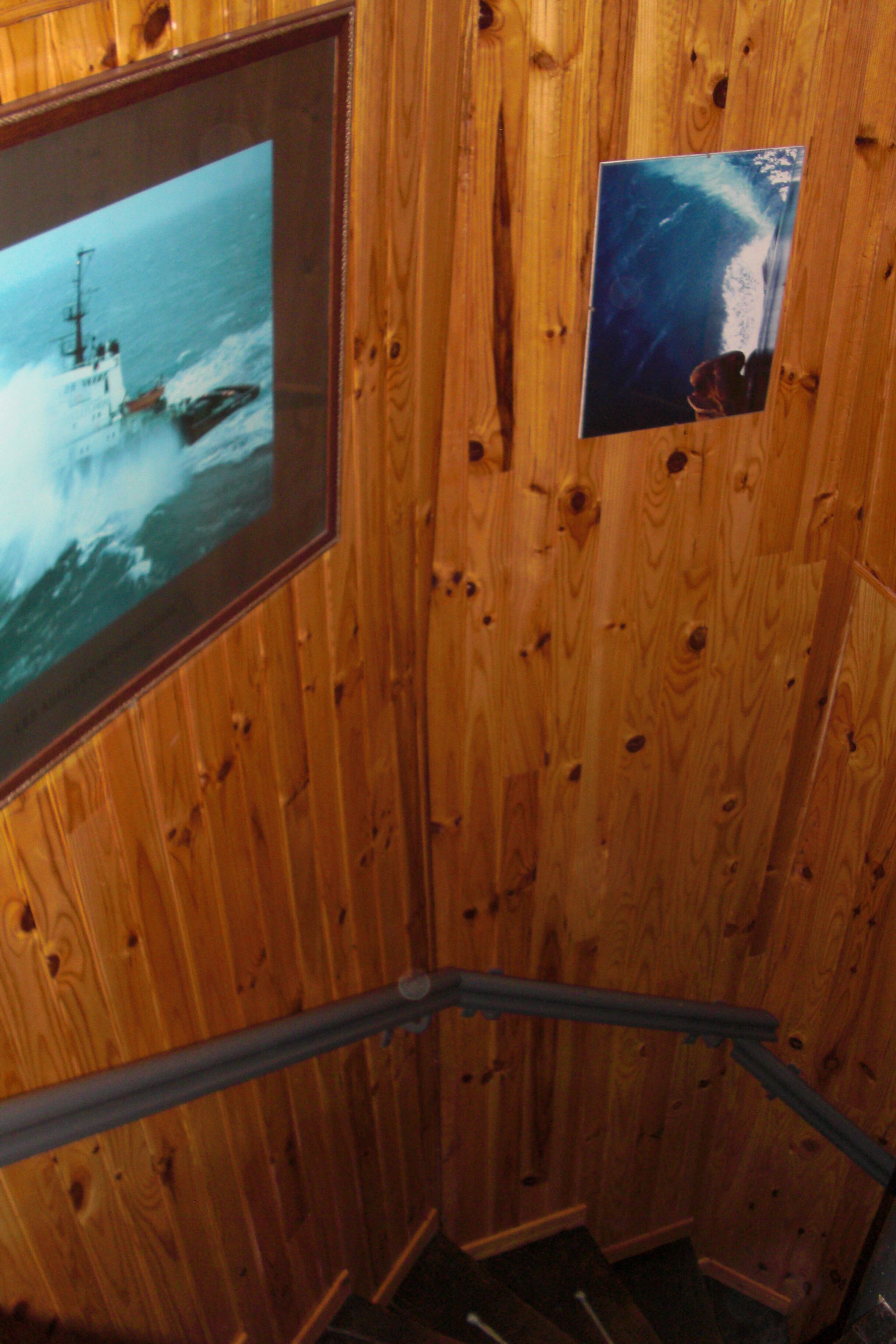 A wooden interior with a framed picture of a boat on the wall.