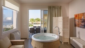 A balcony with a hot tub, wicker furniture, and a view of palm trees and buildings.