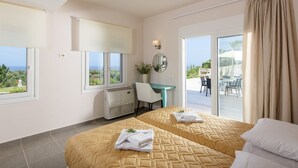 A hotel room with two beds, a desk, a chair, a heater, and a view of the outdoors.