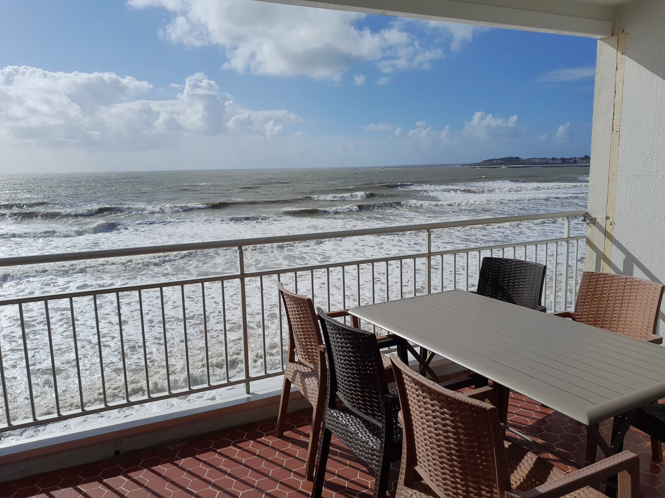 A balcony with a table and chairs overlooking the ocean.