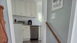 A staircase leading to a kitchen with white cabinets and a stainless steel dishwasher. - Paradise in Port Bay (Wolcott)