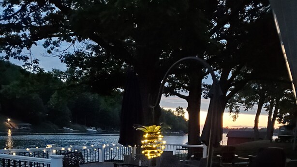 An outdoor patio with a dining area, a decorative light fixture, and a view of a body of water. - Paradise in Port Bay (Wolcott)