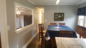 A dining area with a table set for four, wooden chairs, a marble countertop, and a painting on the wall. - Paradise in Port Bay (Wolcott)