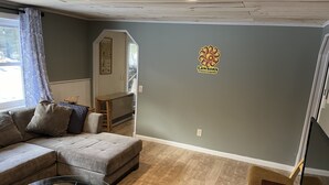 Een woonkamer met een hoekbank, een glazen salontafel en een houten vloer.