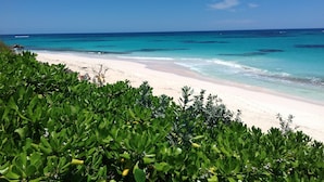 Ein Strand mit klarem türkisfarbenem Wasser und weißem Sand.