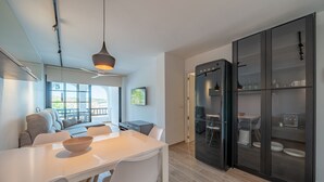 Een moderne keuken met een witte eettafel, een zwarte koelkast en grote ramen.