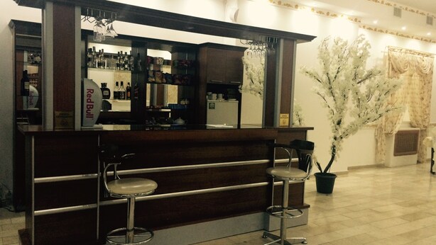 Eine Bar mit zwei Barhocker, einer Theke voller Flaschen und einem Blumentopf.
