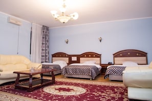 Une chambre d’hôtel avec deux lits, un canapé, une table basse en bois et un lustre.