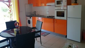 A compact kitchen with orange cabinets, a white refrigerator, a microwave, and a gas stove. - RENTAL 5 ROOM SUN HOLLIDAYS ANY COMFORT SAINTE-ANNE GUADELOUPE (Sainte-Anne)