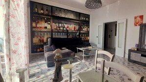 A living room with a sofa, a coffee table, a dining table with chairs, a TV, and a wall of liquor bottles. - Seaview dream home (Conca dei Marini)