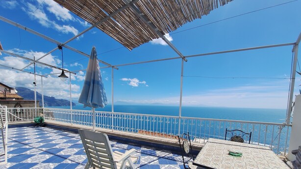 A terrace with a patterned floor, a table, chairs, and a view of the sea. - Seaview dream home (Conca dei Marini)