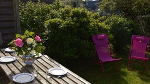 A wooden picnic table set outdoors with plates, cutlery, and a vase of flowers. - SAND GRAIN *** STARS 700 METERS FROM THE BEACHES BETWEEN CANCALE AND SAINT MALO (Saint-Coulomb)