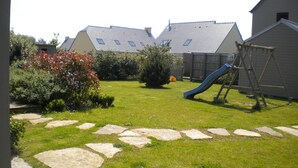 A backyard with a stone pathway, a slide, and a play structure. - SAND GRAIN *** STARS 700 METERS FROM THE BEACHES BETWEEN CANCALE AND SAINT MALO (Saint-Coulomb)