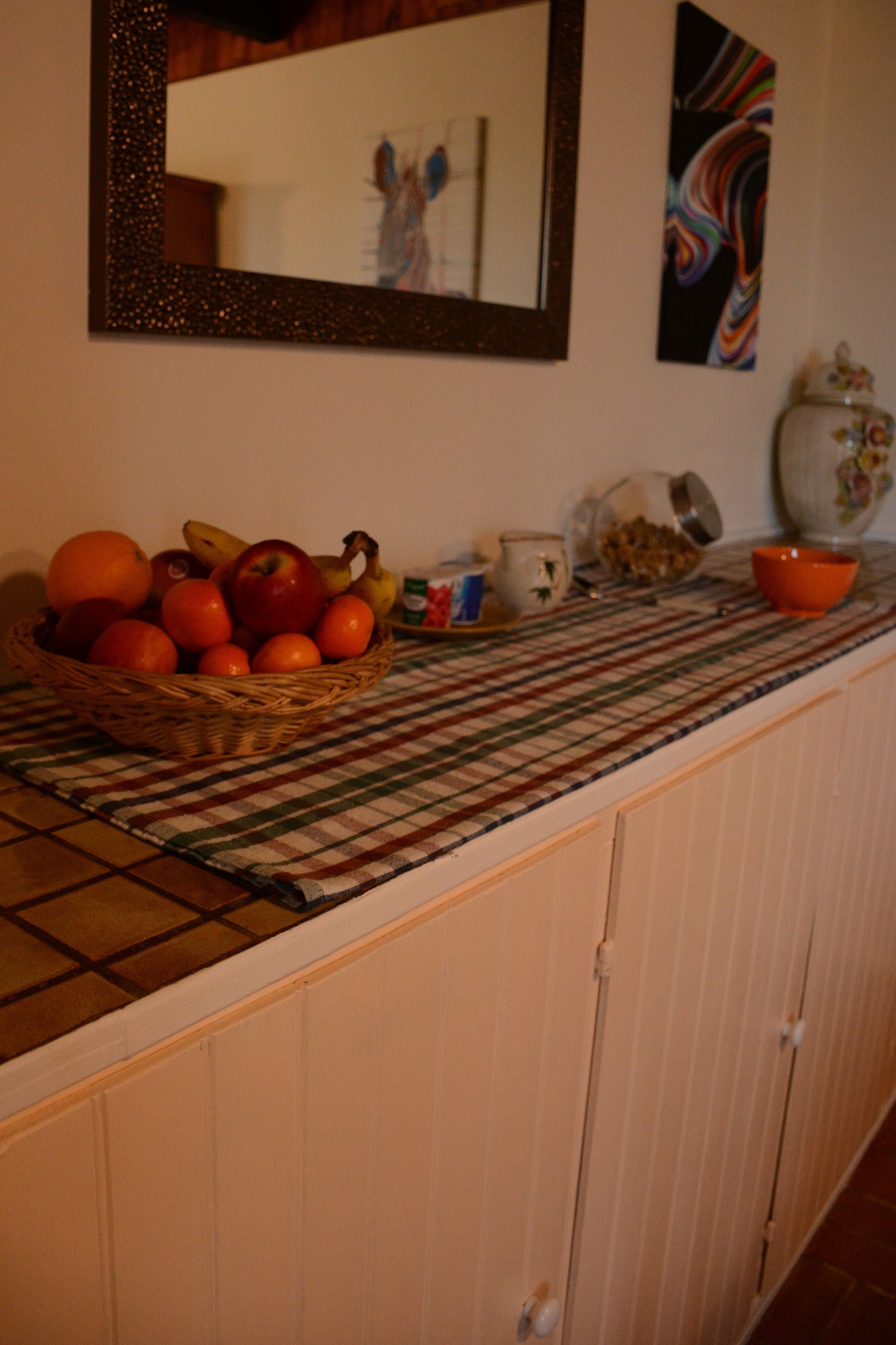 Una encimera de cocina con una cesta de fruta, un bol y una cafetera.
