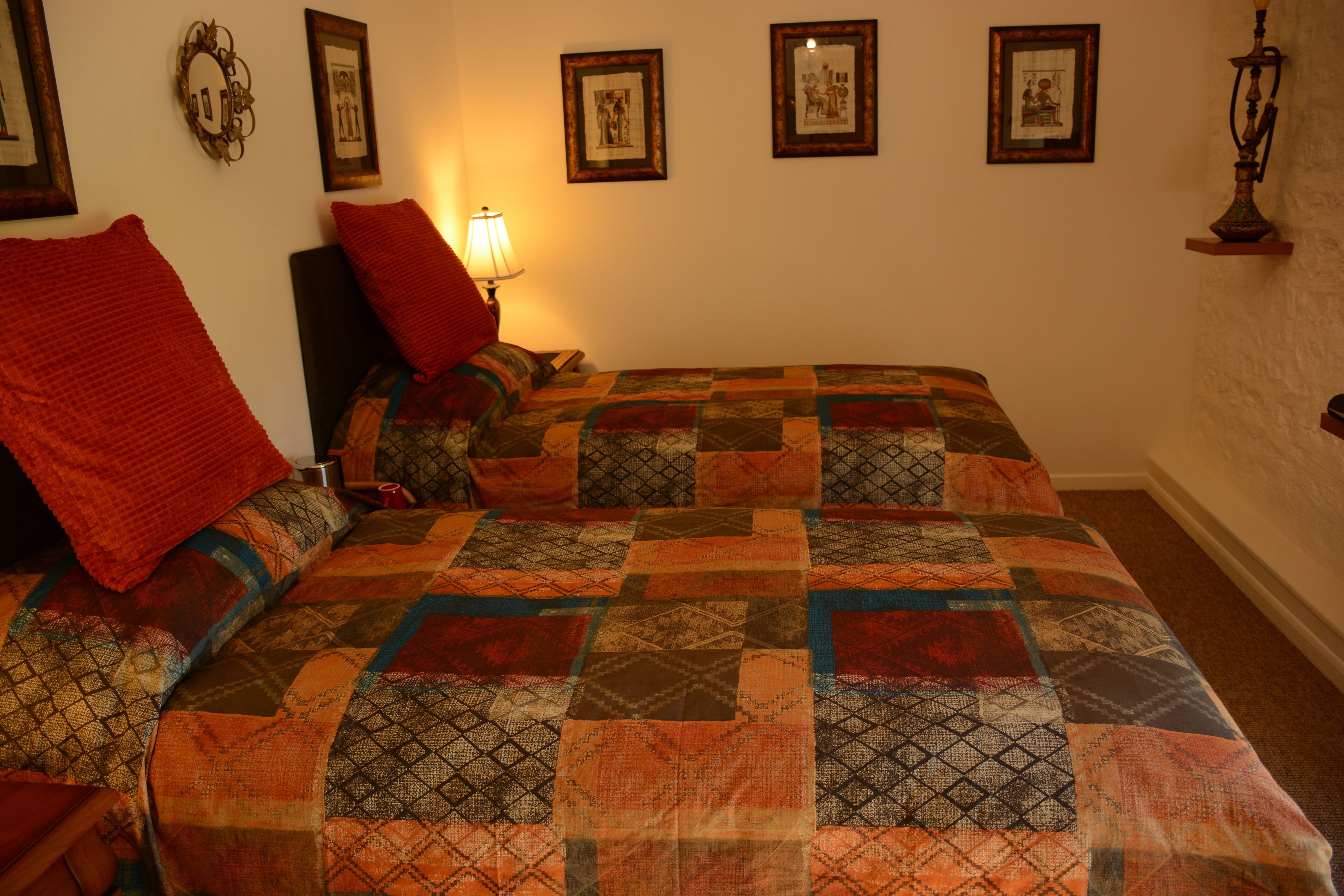 Une chambre à coucher avec un grand lit, de nombreux oreillers, une lampe de chevet et des tableaux encadrés accrochés au mur.