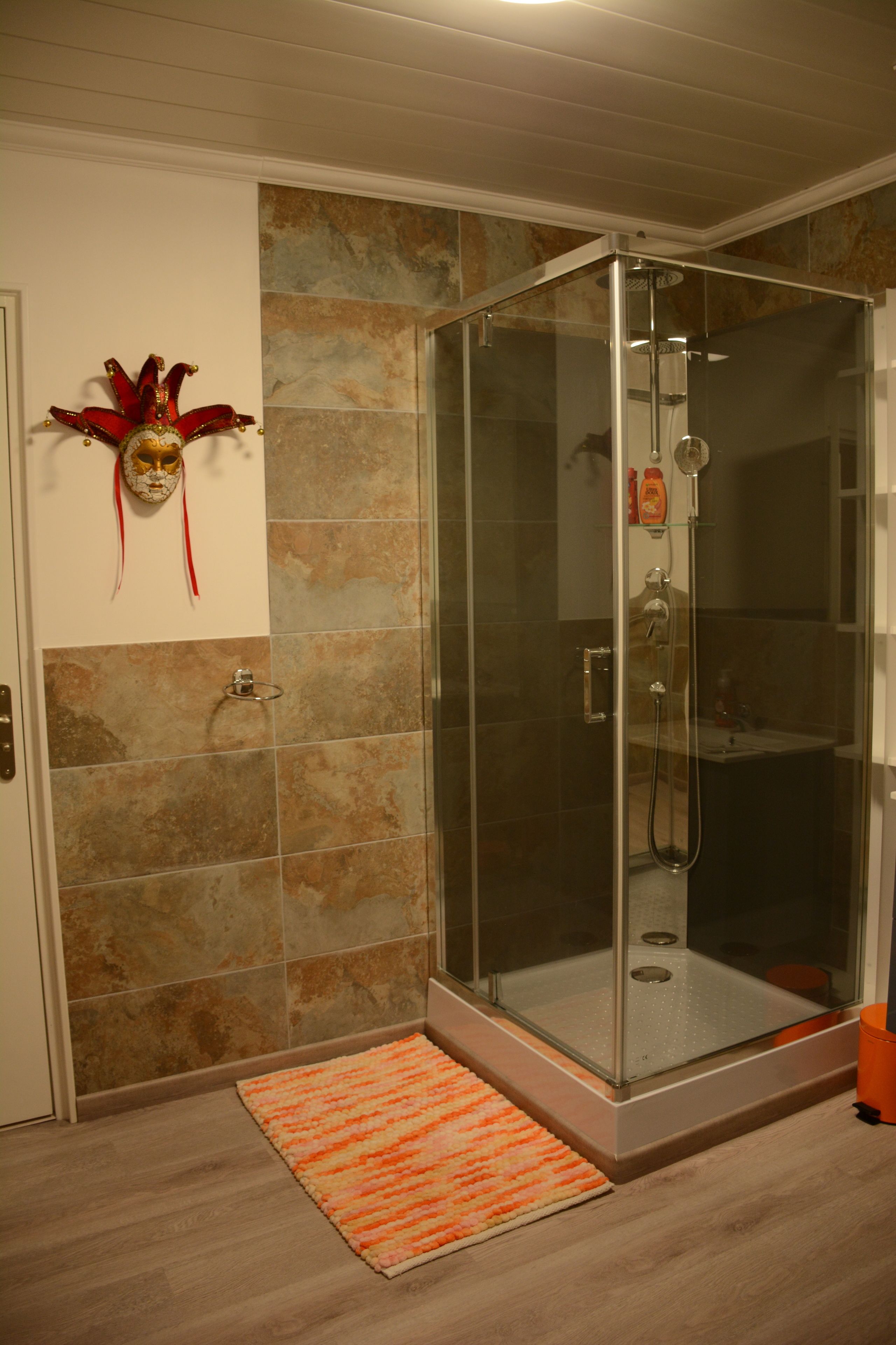 A shower area with a glass door, a hand dryer, and a towel rack.