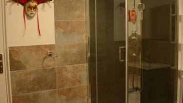 A shower area with a glass door, a hand dryer, and a towel rack.