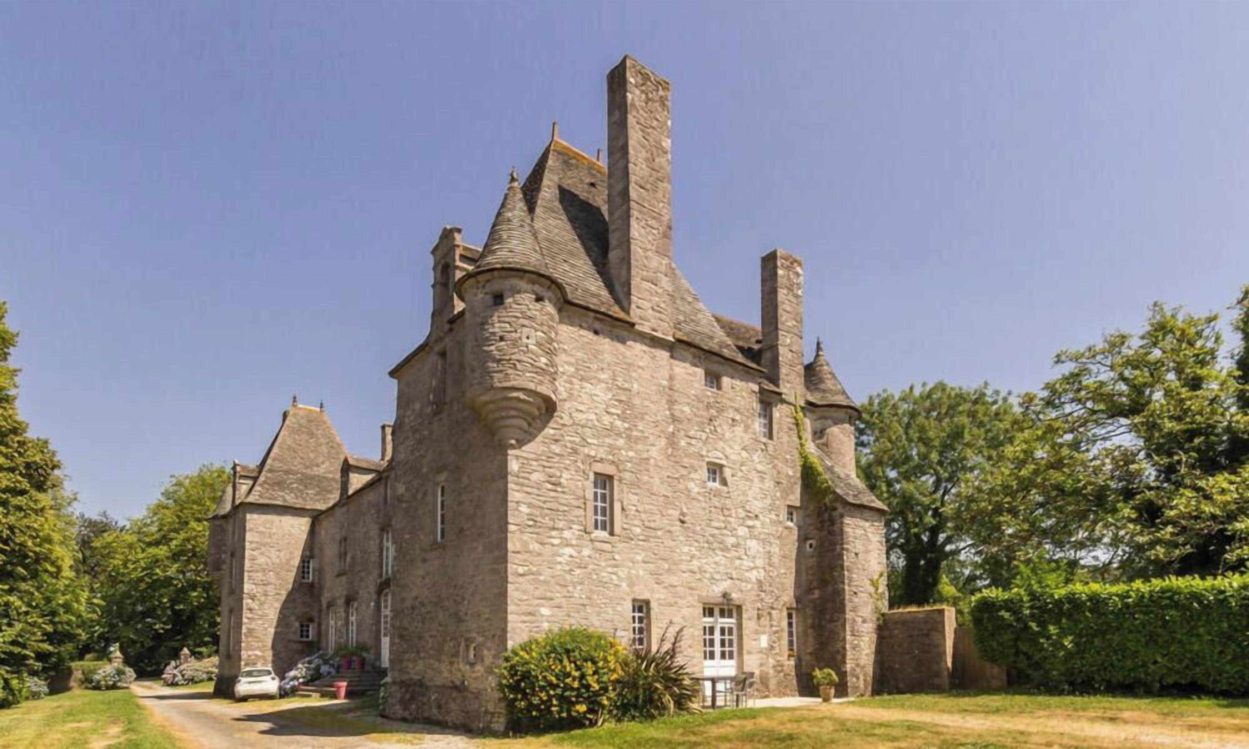 A stone castle with multiple towers and a well-maintained garden.