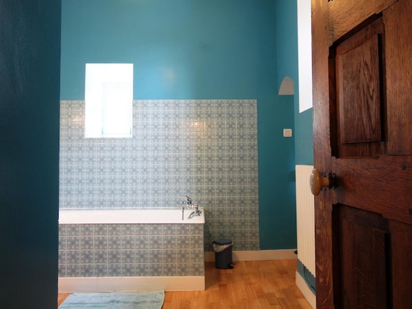 Ein Badezimmer mit einer Badewanne, einem Fenster und einer Tür.