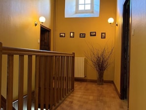 Ein Flur mit Holzbalken, einem Heizkörper und gerahmten Bildern an der Wand.
