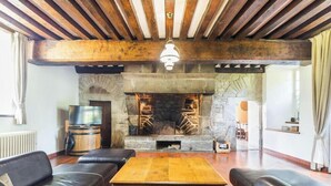 A cozy living room with a stone fireplace, leather sofas, a wooden coffee table, and a television on a barrel.