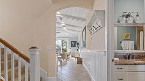 A spacious hallway with a staircase, a dining area, and a bathroom with a vanity and sink. - Minnie Cottage- Beautiful 3 bedroom heated pool/spa and short walk to the beach (Holmes Beach)