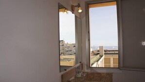 A bathroom with a large window, a sink, and a mirror.