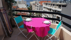 A balcony with a table set for two, chairs, and a view of the cityscape.