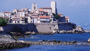 A coastal town with historic stone buildings and a prominent tower.
