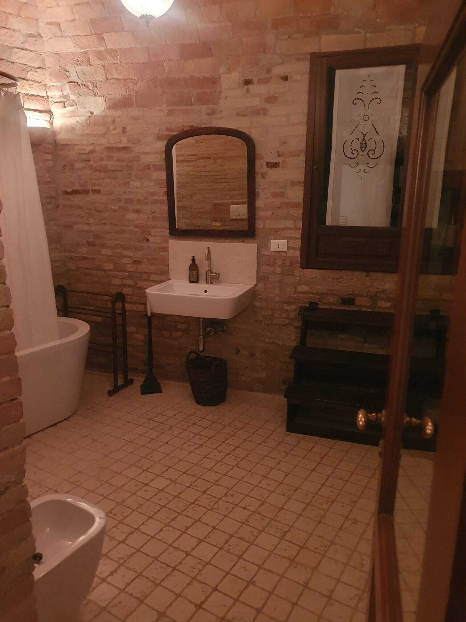 Un baño con lavamanos blanco, espejo, bañera y retrete.
