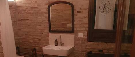 Un baño con lavamanos blanco, espejo, bañera y retrete.