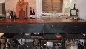 Una cocina con encimera de madera, botellas de vino, tabla de cortar y diversos utensilios de cocina.