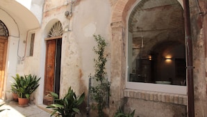 Un edificio con ventanas y puertas arqueadas, plantas en macetas y un interior visible a través de las ventanas.