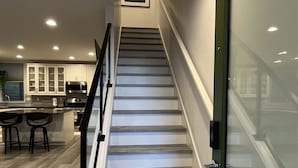 A modern staircase with wooden steps and a glass door at the top. - New centrally located townhouse with rooftop deck. Walk to restaurants and shops (Seattle)