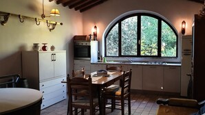 Eine kompakte Küche mit Essbereich, ein großes Fenster mit Blick auf Grünflächen und eine gemütliche Sitzecke.