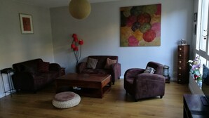 A living room with a wooden floor, two sofas, a coffee table, and a hanging light fixture. - Bohemian chic apartment in the heart of the Antigone district (Montpellier)